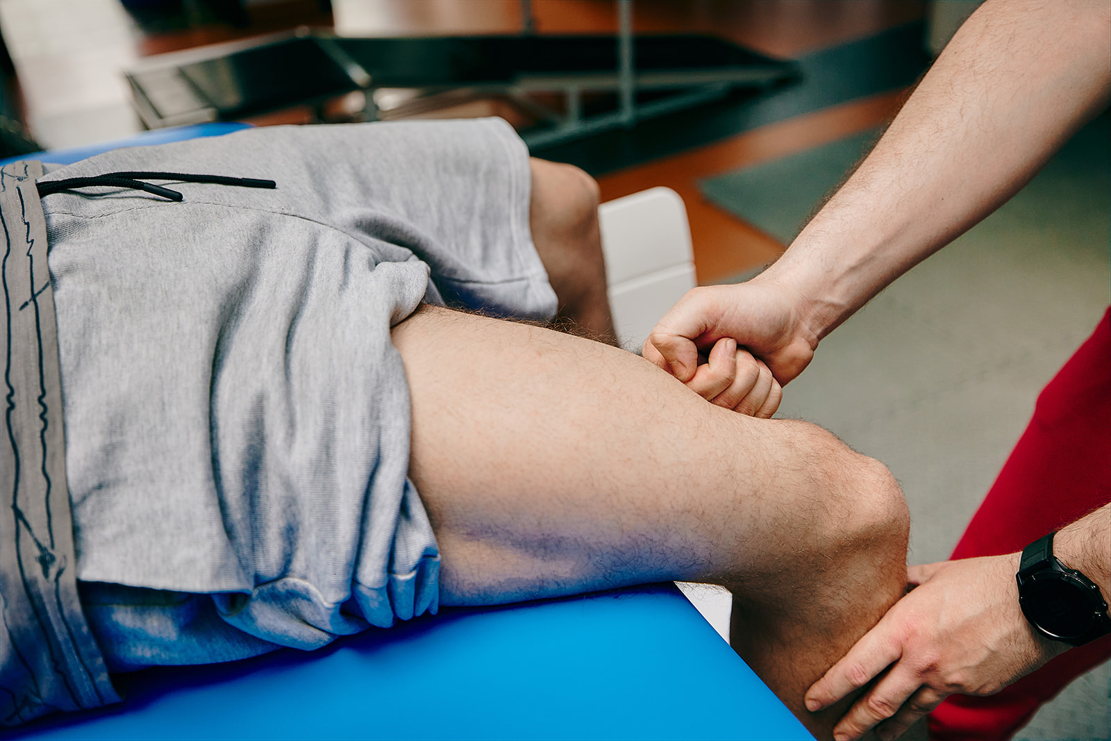 Na zdjęciu zbliżenie na nogę pacjenta masowaną przez fizjoterapeutę.