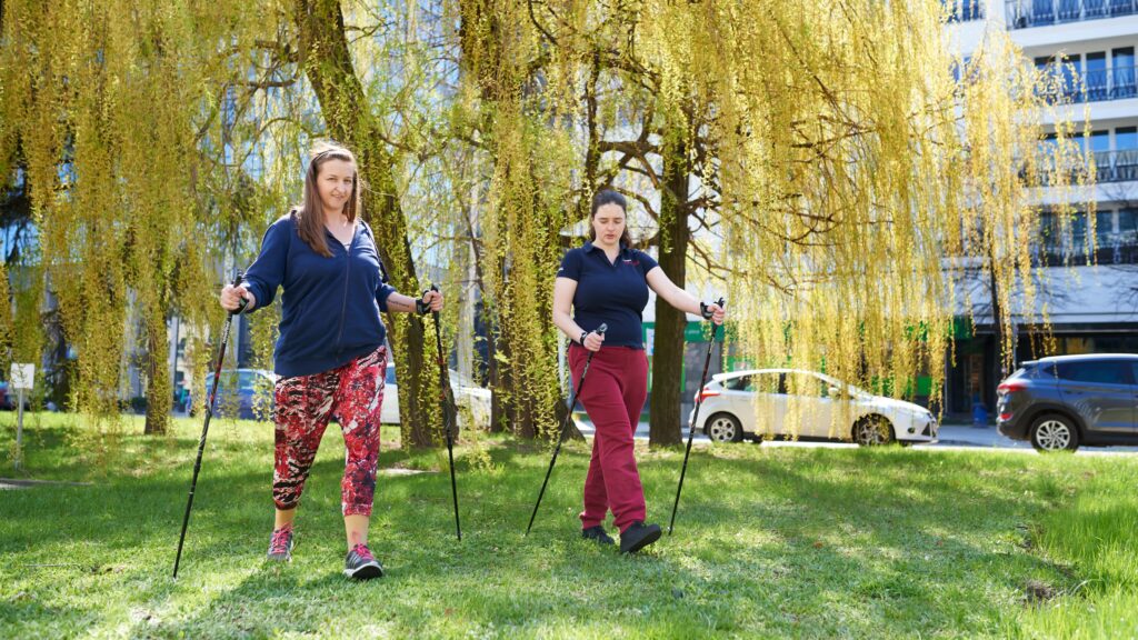 Trenerka i pacjentka podczas zajęć Nordic Walking w plenerze.