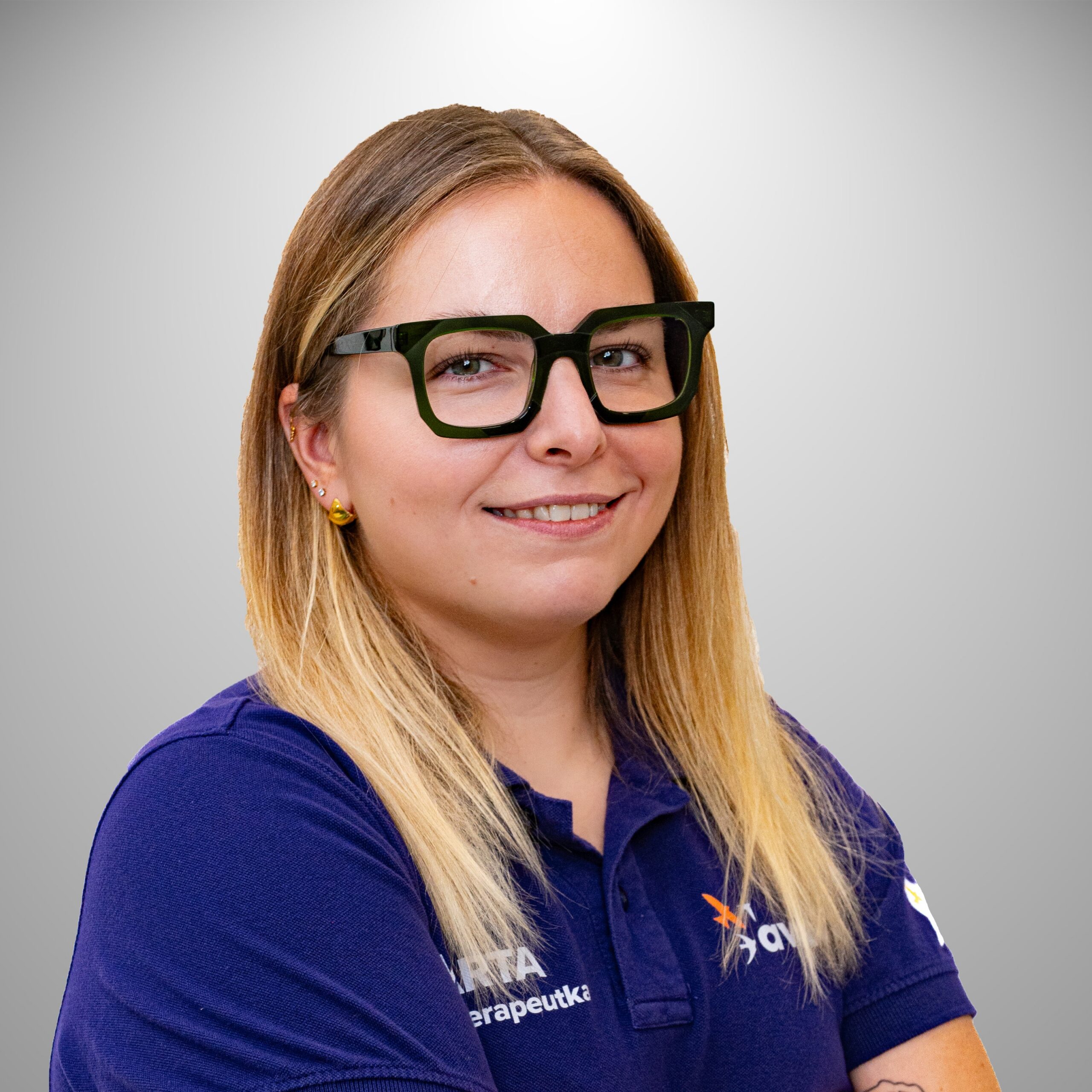 Uśmiechnięta Marta Maik w fioletowej koszulce fizjoterapeuty dziecięcego.