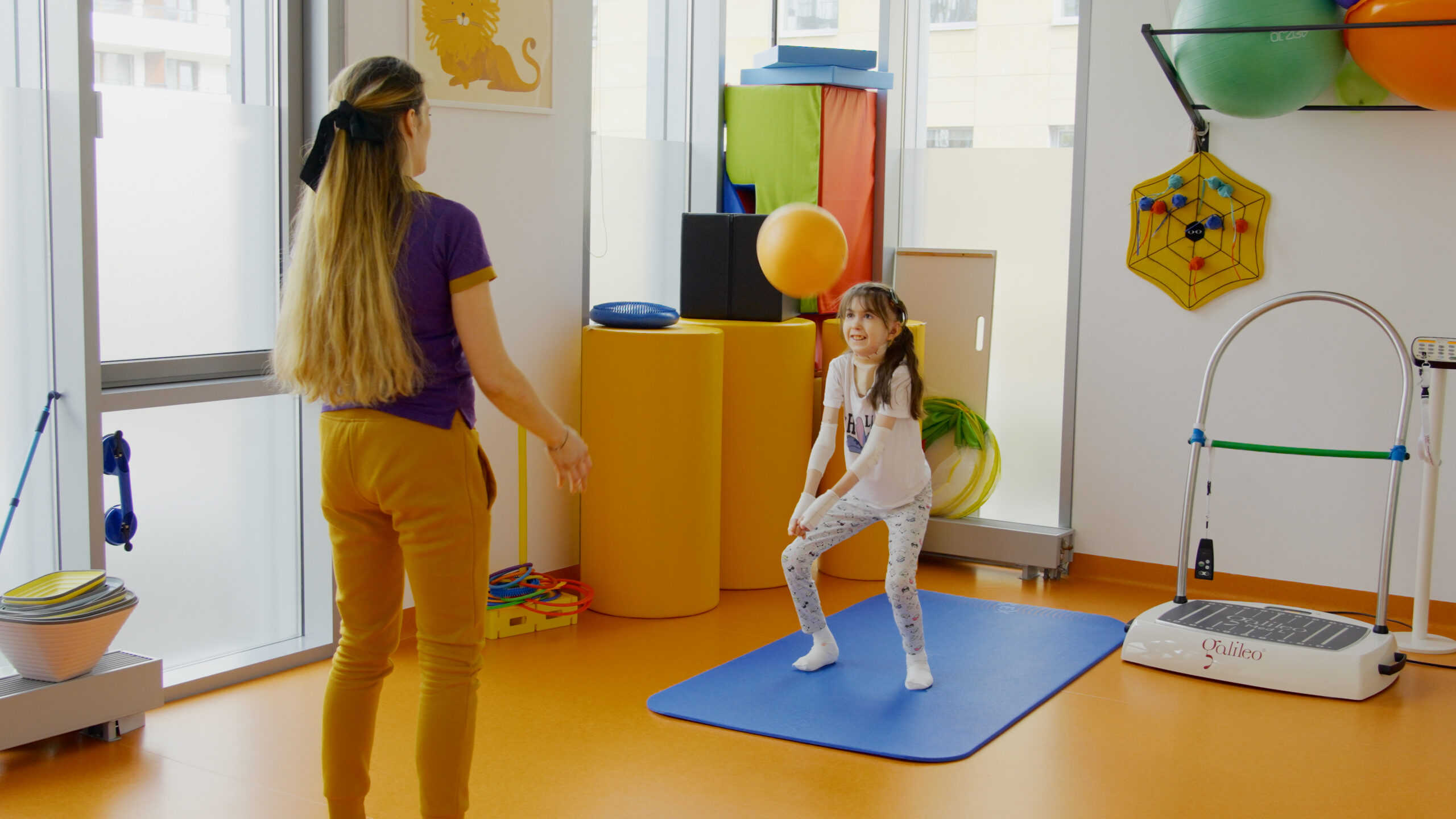 dziewczynka z rehabilitantką podczas zajęć z piłką