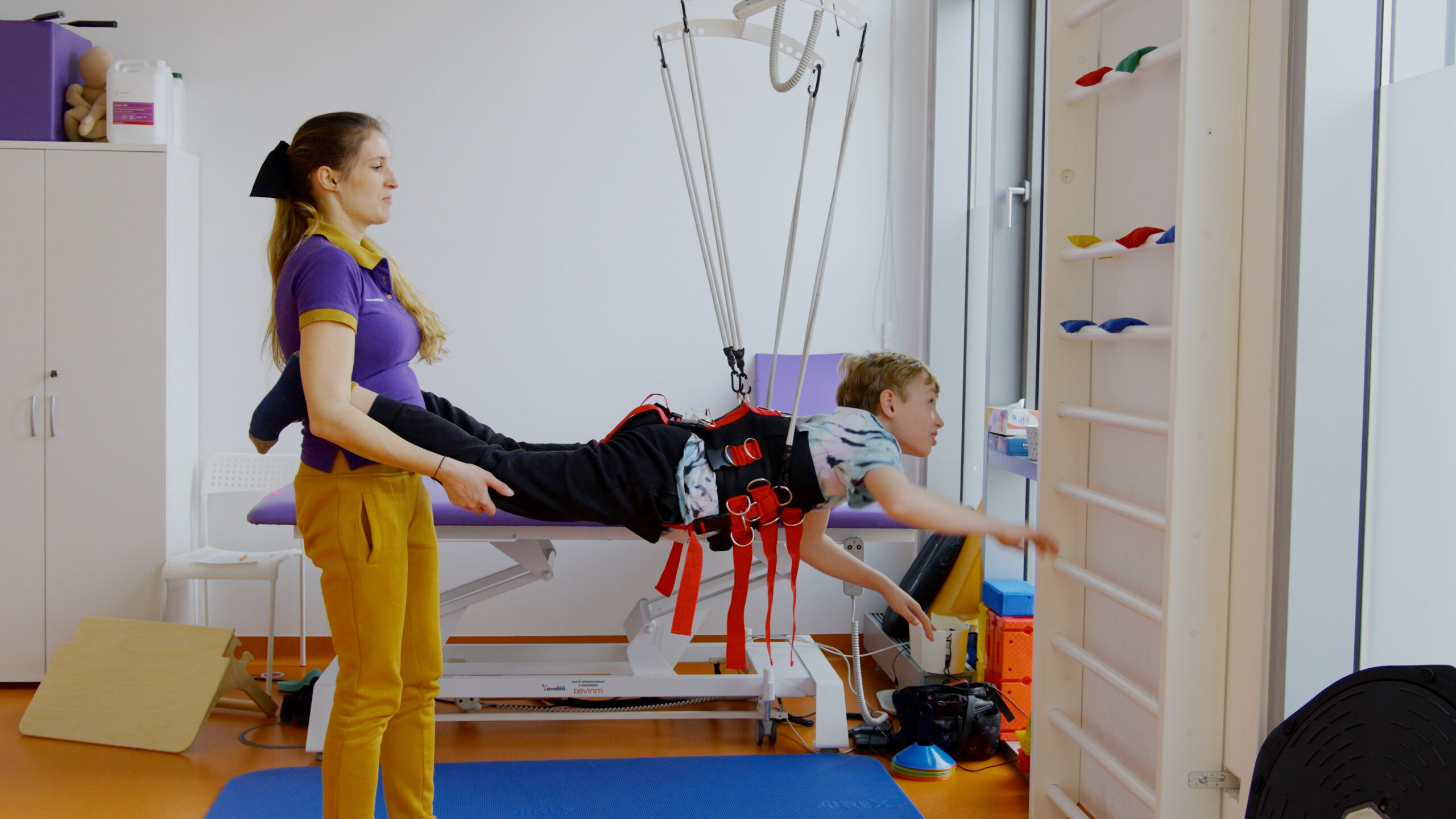 chłopiec z rehabilitantką podczas zajęć na drabince