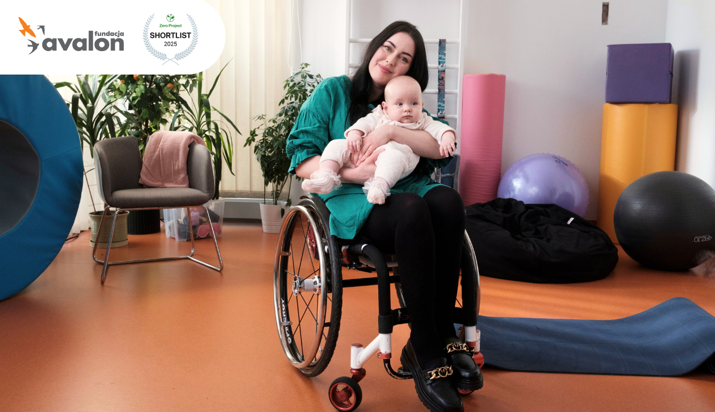 Zdjęcie kobiety na wózku trzymającej na kolanach kilkumiesięczną córeczkę. Są one w sali rehabilitacyjnej, w tle przyrządy do ćwiczeń. W rogu logo Fundacji Avalon oraz znak Zero Project Award 2025