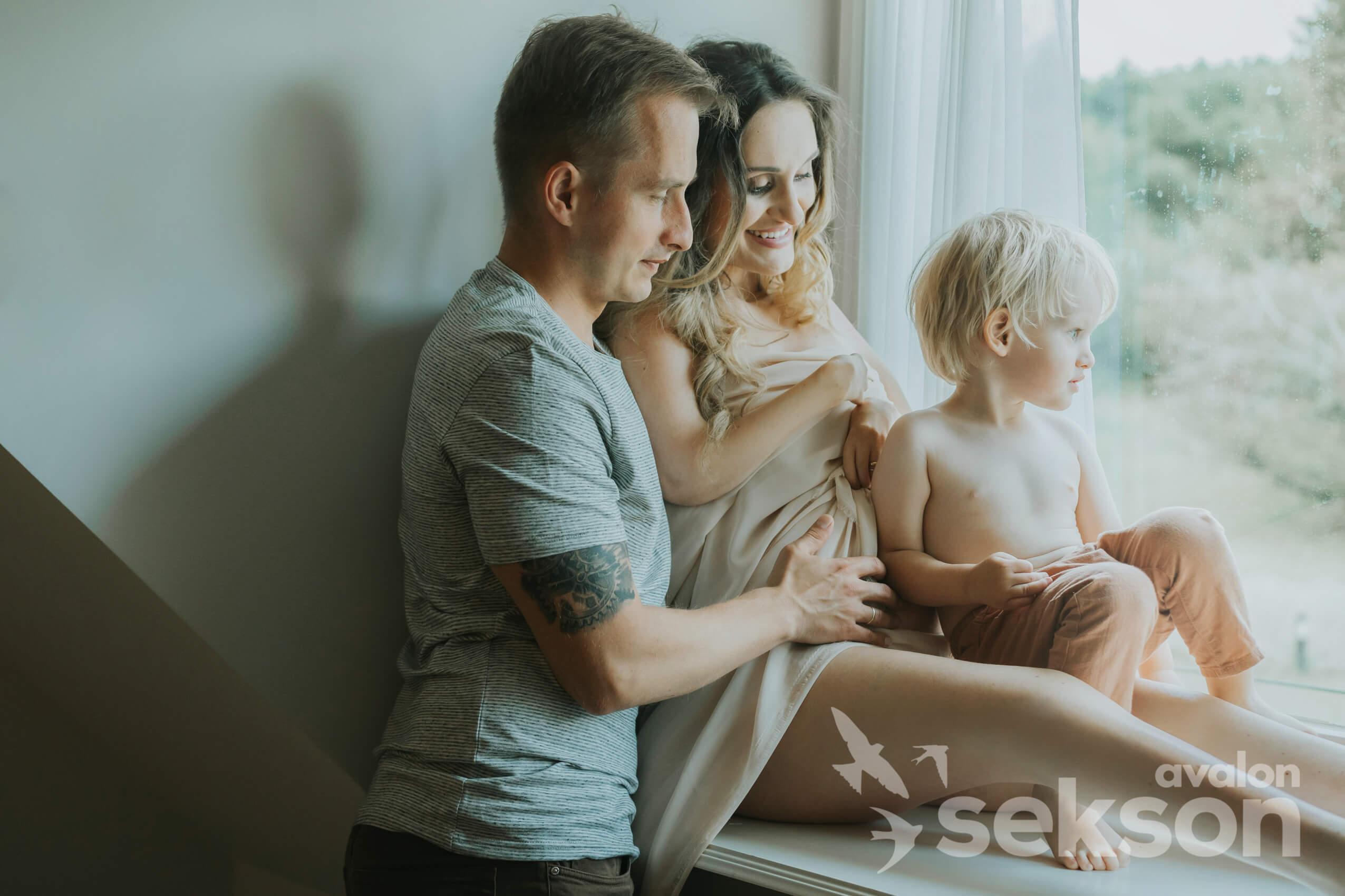 Sylwia i siedzi na parapecie, obok niej stoi Tomasz. W nogach Sylwii siedzi ich synek, Oliwier.