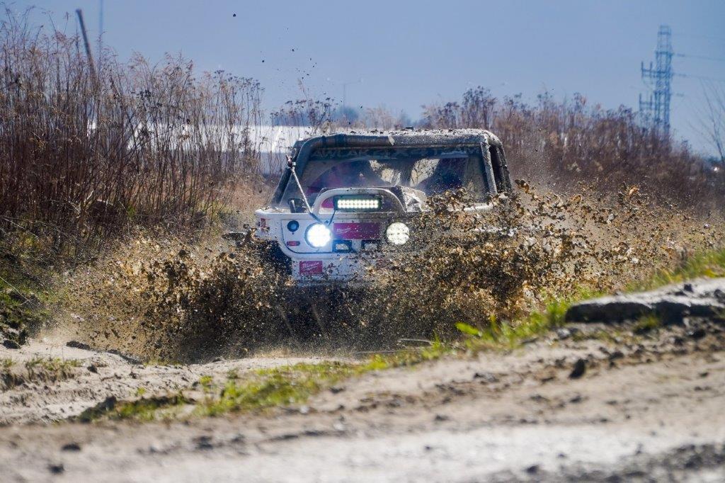 Auto terenowe jedzie po błocie, rozpryskując je wokół.