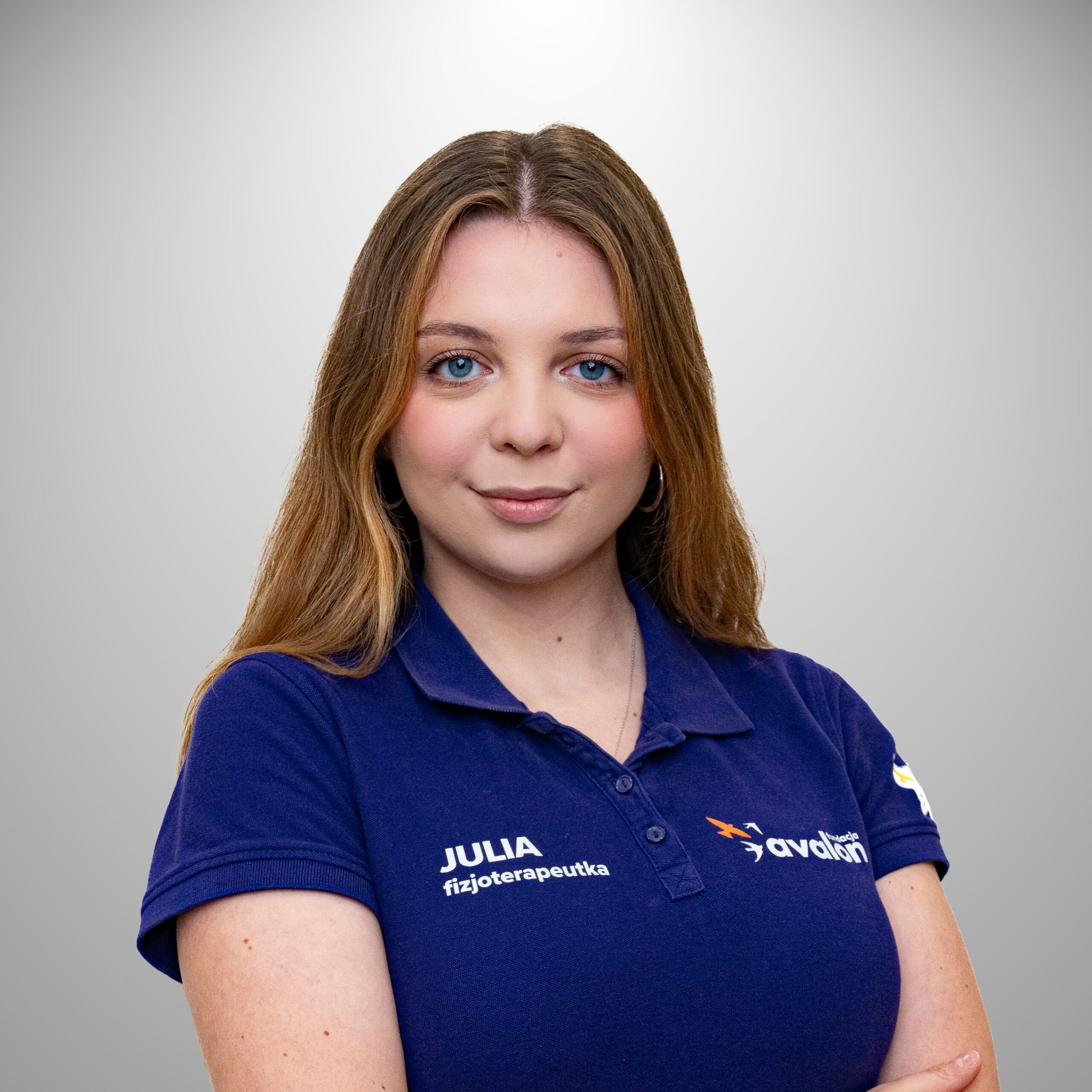 Uśmiechnięta Julia Szczygieł w fioletowej koszulce fizjoterapeuty dziecięcego.