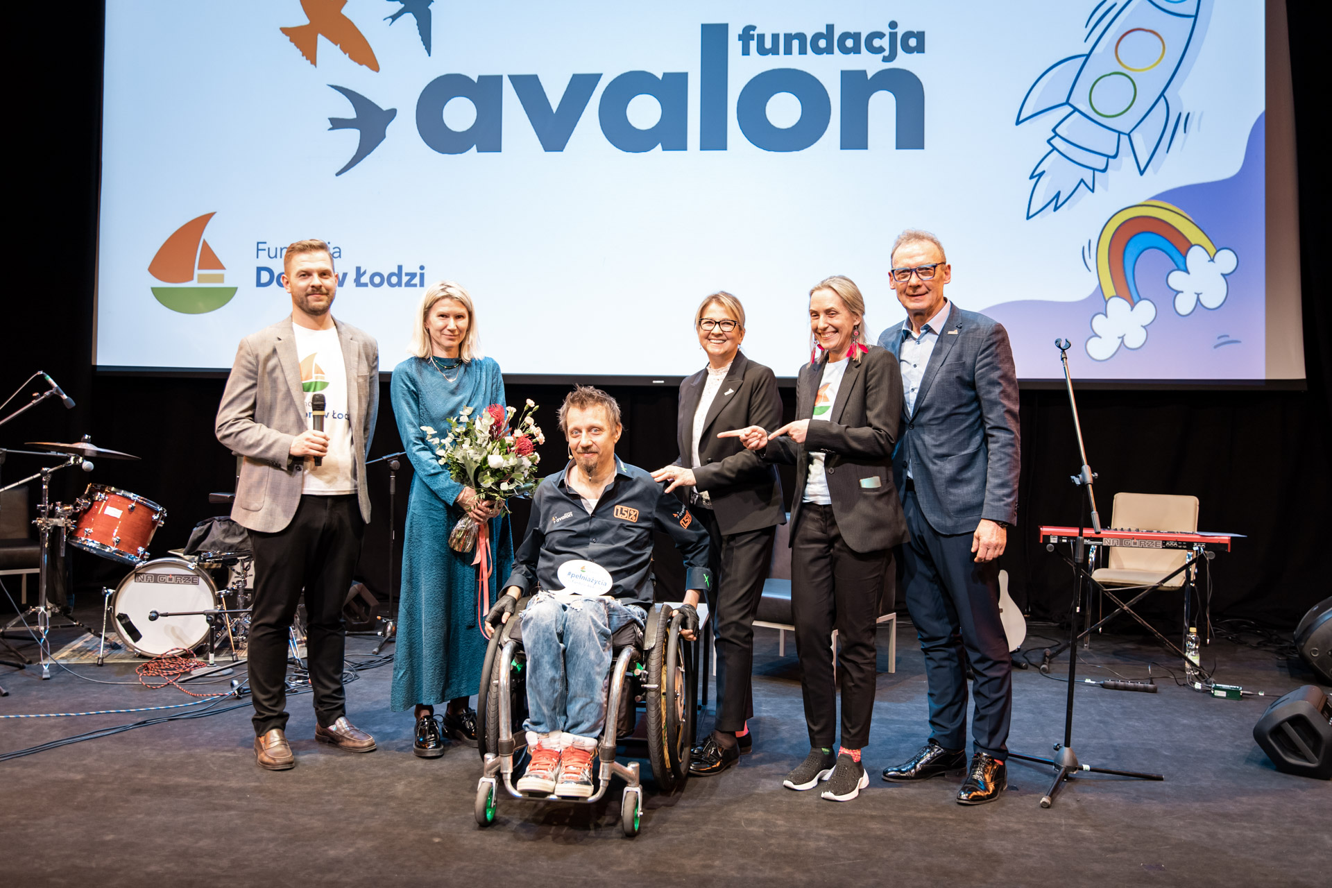 Sebastaian Lusty na scenie Festiwalu Pełnia Życia z nagrodą. Jest w towarzystwie przedstawicieli Fundacji