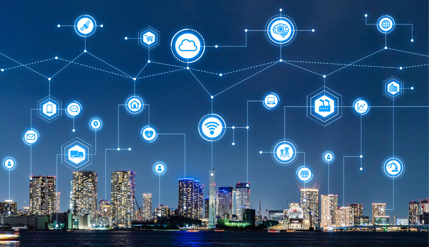 Nowoczesne inteligentne miasto nocą z ikonami technologii IoT, chmury, łączności i przemysłu, symbolizującymi cyfrową transformację.