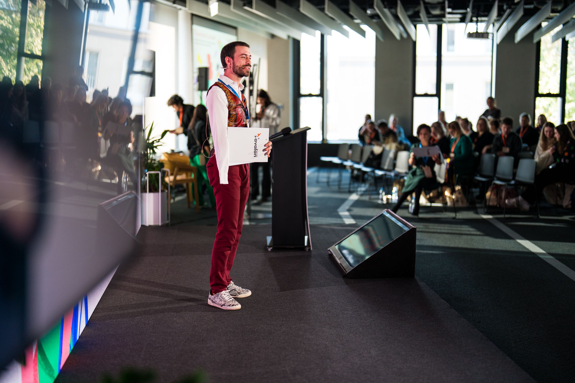 Jan Mela przed pulpitem na scenie VI KonferencjiSekson - w tle publiczność.