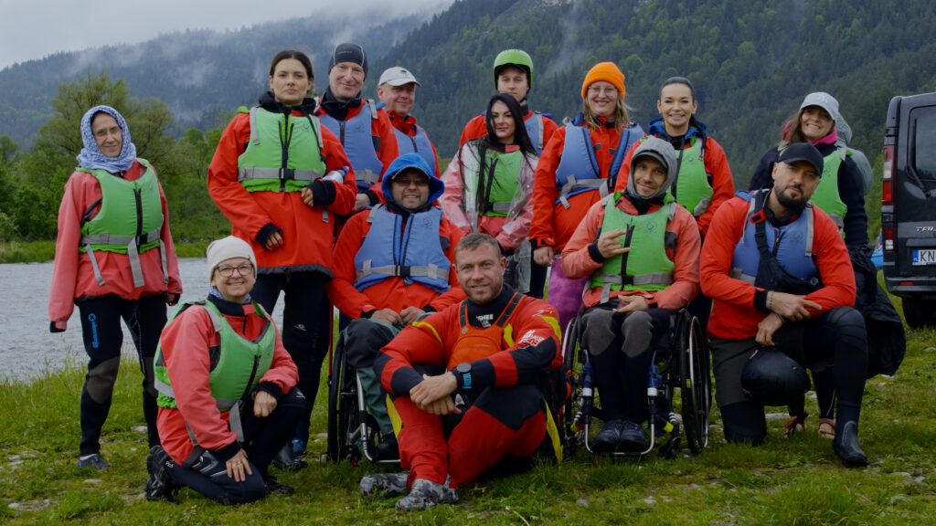 Zdjęcie grupy wyjazdowej - Rafting w Pieninach; w tle zalesione zbocza gór.