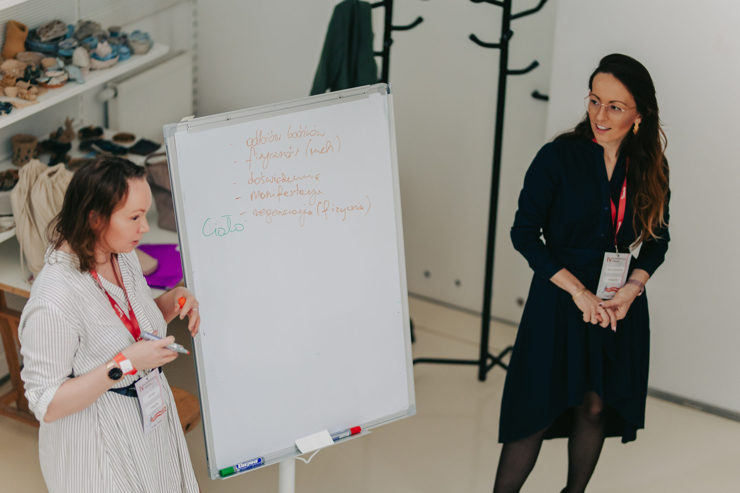 dwie kobiety prowadzą szkolenie, stoją przy białej tablicy
