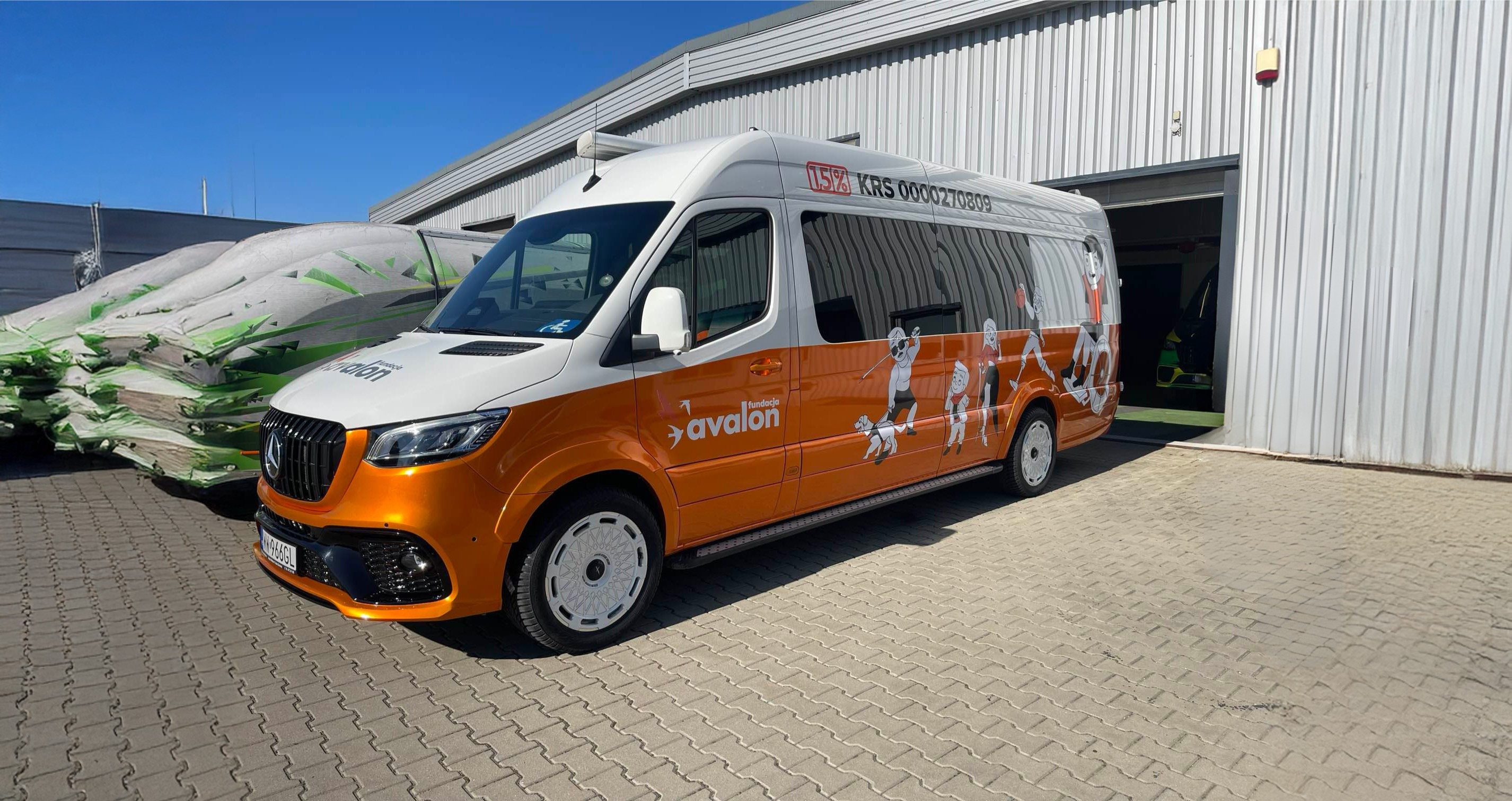 Projekt bez nazwy (18) (1) Pomarańczowo-biały bus z logotypem Fundacji Avalon, numerem KRS oraz ilustracjami przedstawiającymi osoby z różnymi niepełnosprawnościami.