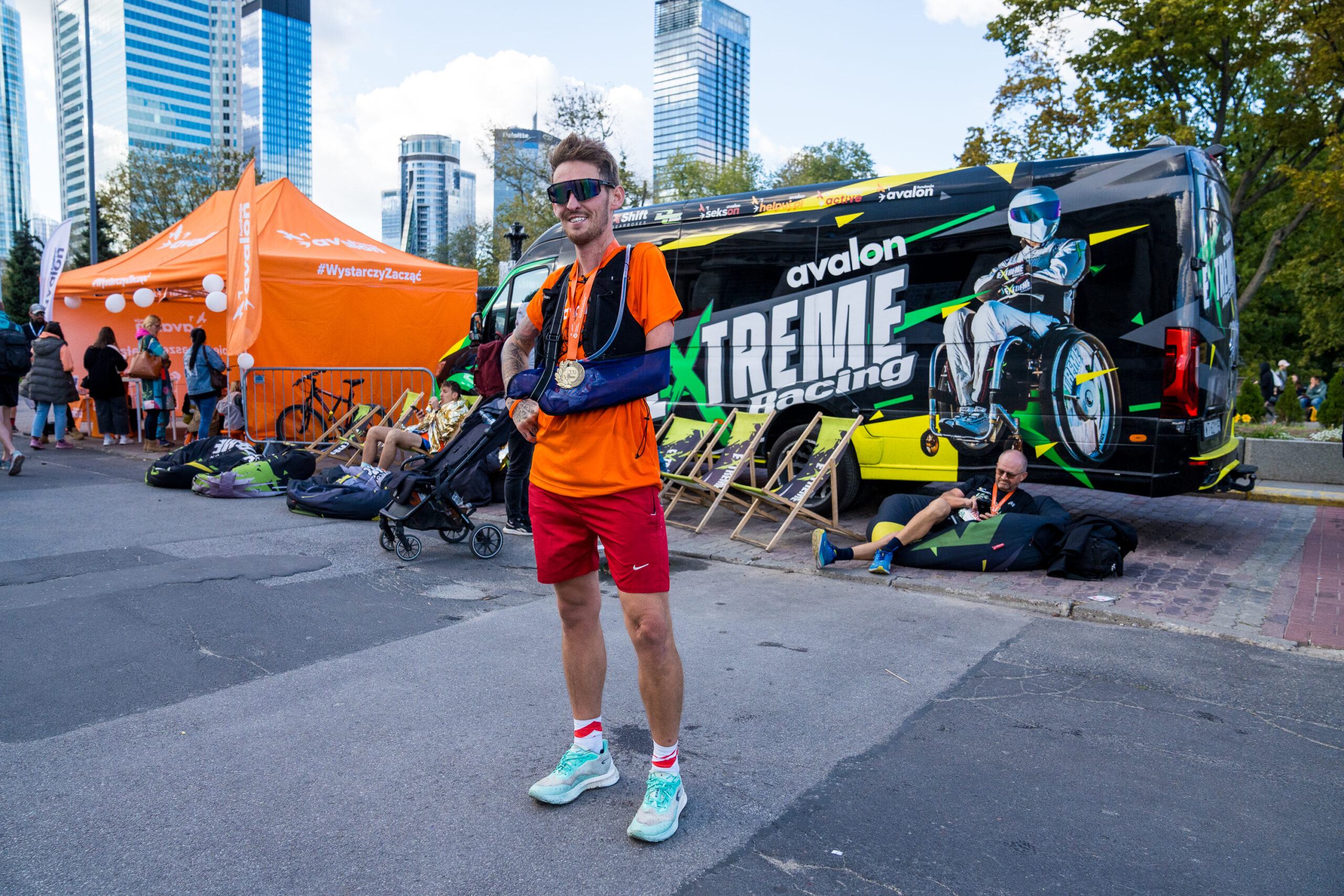 Grzegorz Karpiński pozuje na tle busa Avalon Extreme oraz namiotu Fundacji Avalon.