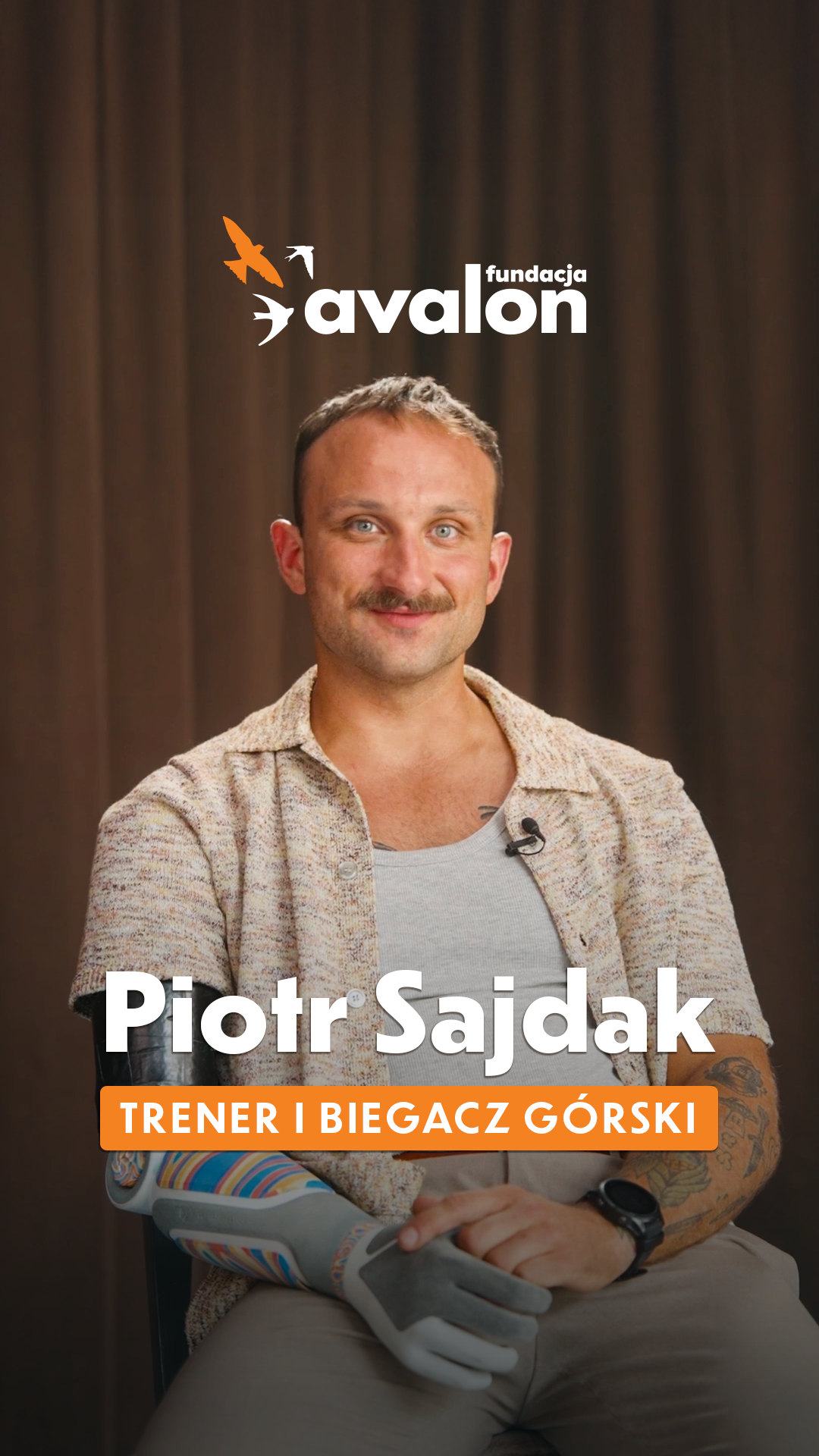 Uśmiechnięty Piotr w jasnej koszuli z krótkim rękawkiem. napis Piotr Sajdak: Trener i biegacz górski.