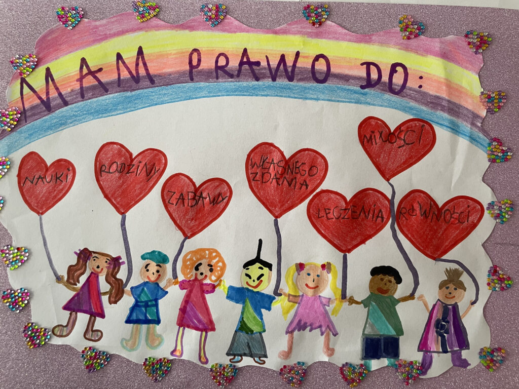 Na rysunku siedmioro różnorodnych dzieci, każde z nich trzyma balonik w kształcie serca z nazwą jednego prawa. Są to prawo do: nauki, rodziny, zabawy, własnego zdania, leczenia, miłości i równości. Nad nimi tęcza.