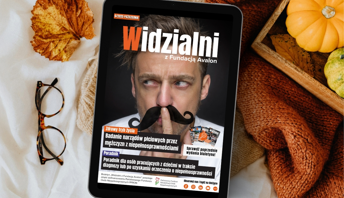 „Tablet leżący na białej tkaninie obok okularów, pomarańczowego koca i koszyka z dyniami. Na ekranie widoczna jest okładka magazynu ‘Widzialni’ przedstawiająca mężczyznę z doklejonym czarnym wąsem.”