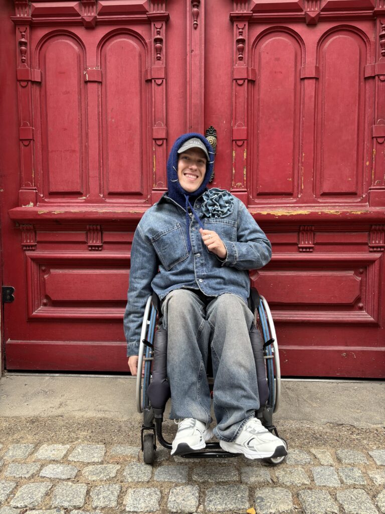 Norbert Tumidaj na wózku w dzinsowej kurtce i spodniach.