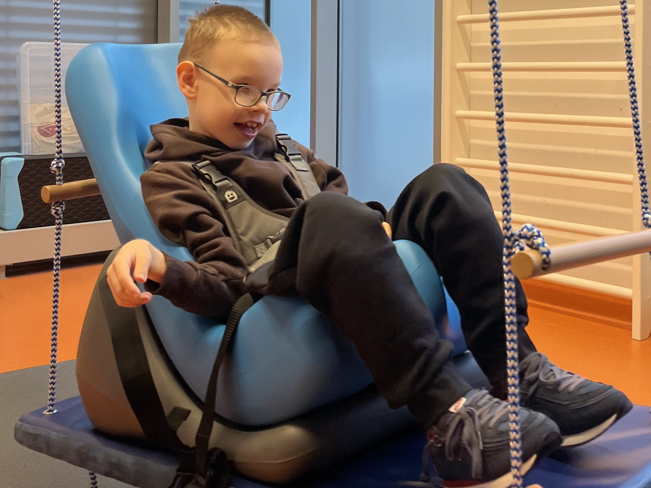 Uśmiechnięty chlopiec w specalistycznym siedzisku.