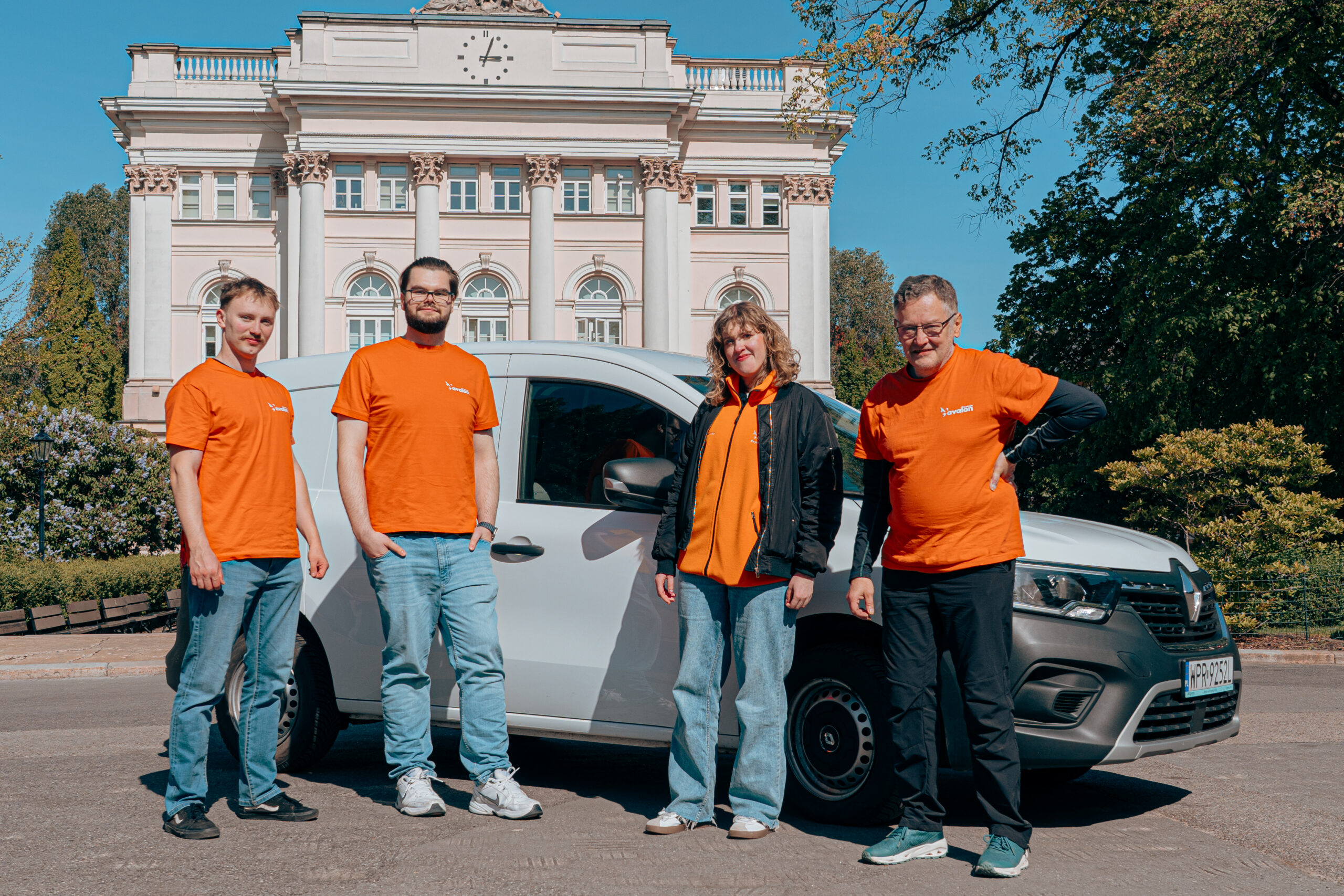 Grupa wolontariuszy na tle samochodu Ayvens. Są na dziedzińcu Uniwersytetu Warszawskiego.