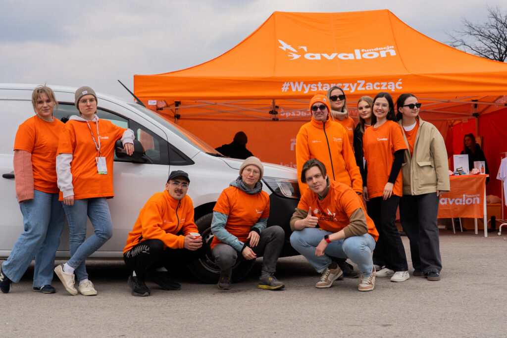 Grupa wolontariuszy Fundacji na tle samochodu z firmy Ayvens.