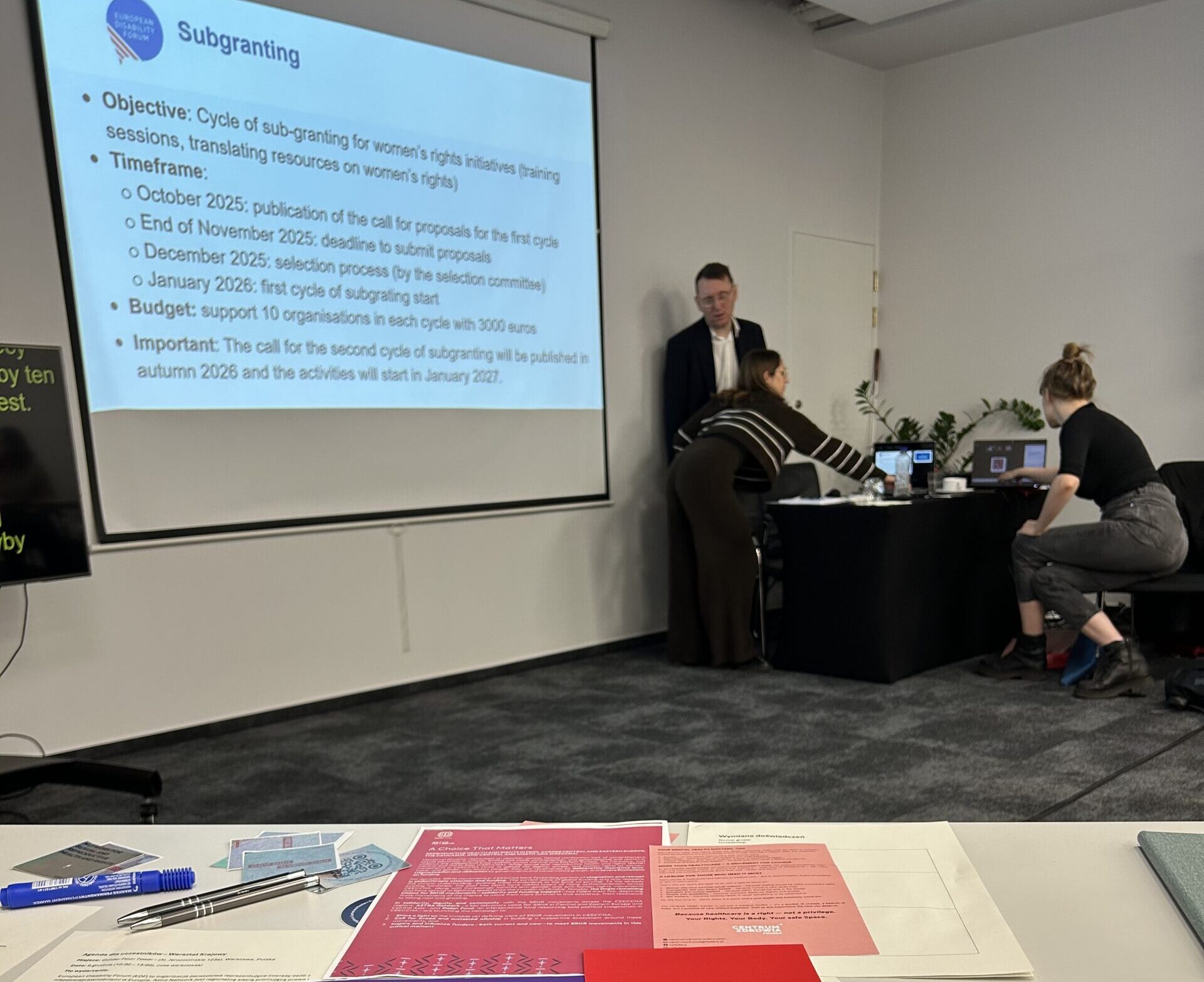 sala konferencyjna, na ścianie wyświetla się slajd prezentacji