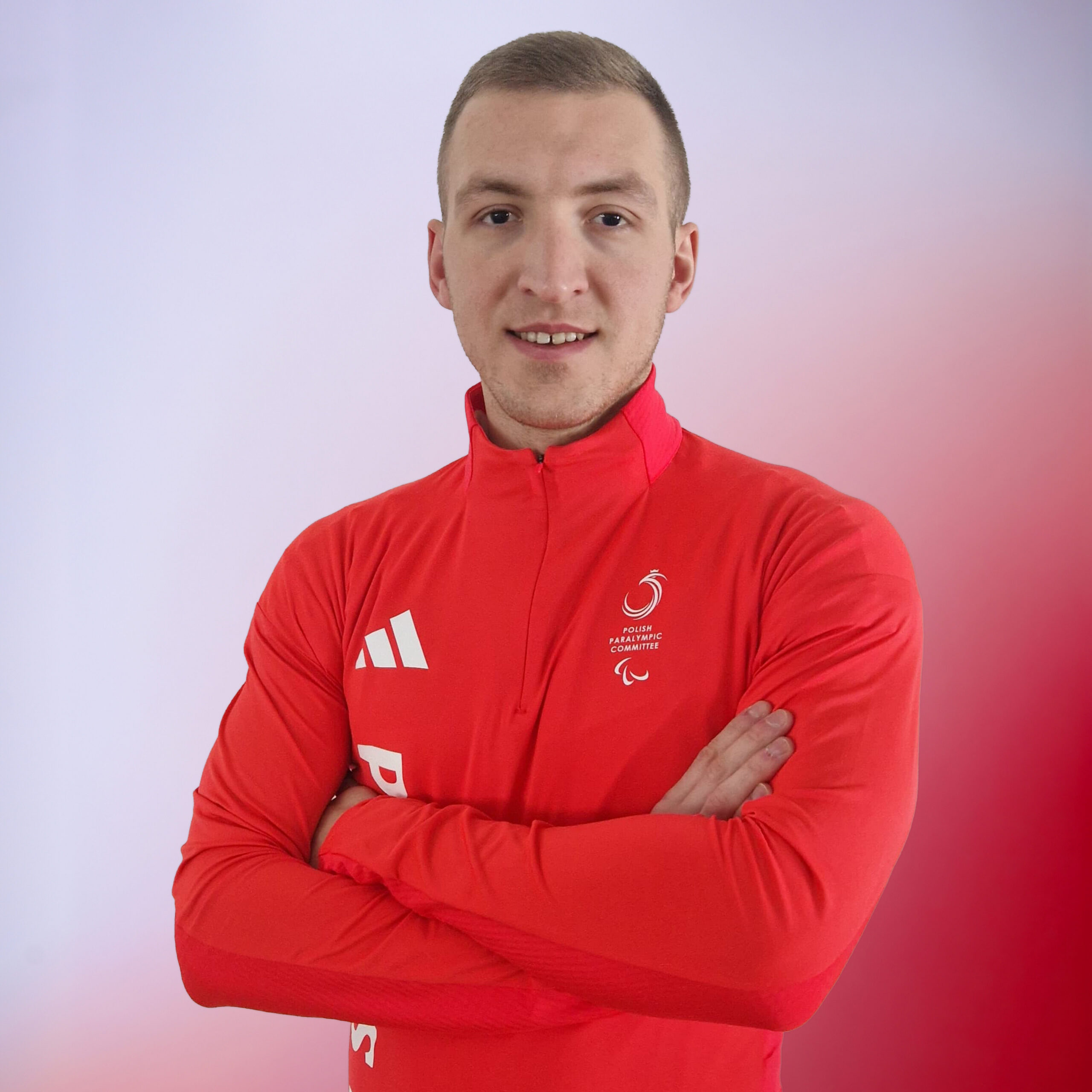 sportowiec reprezentacji w Igrzyskach Paralimpijskich pozuje do zdjęcia w czerwonym stroju sportowym