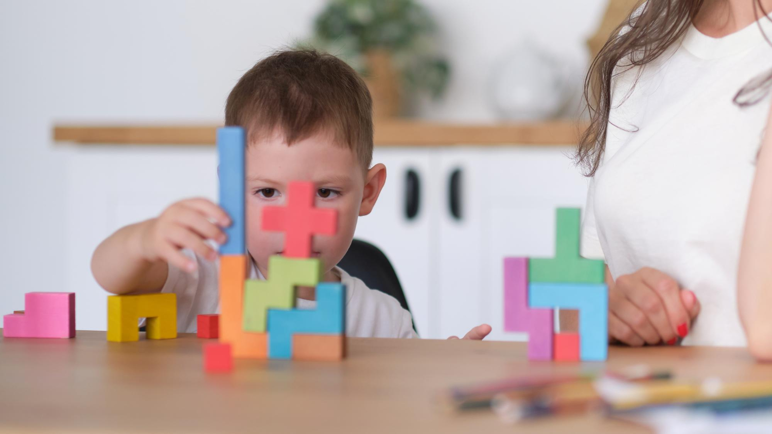 Małe dziecko układa klocki przy stoliku