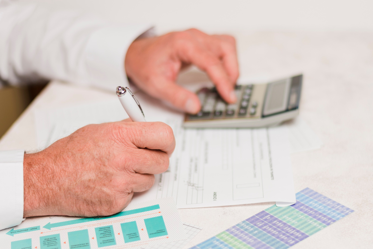 Widzimy ręce starszego Pana, który zapisuje coś na kartce - prawdopodobnie wynik z kalkulatora